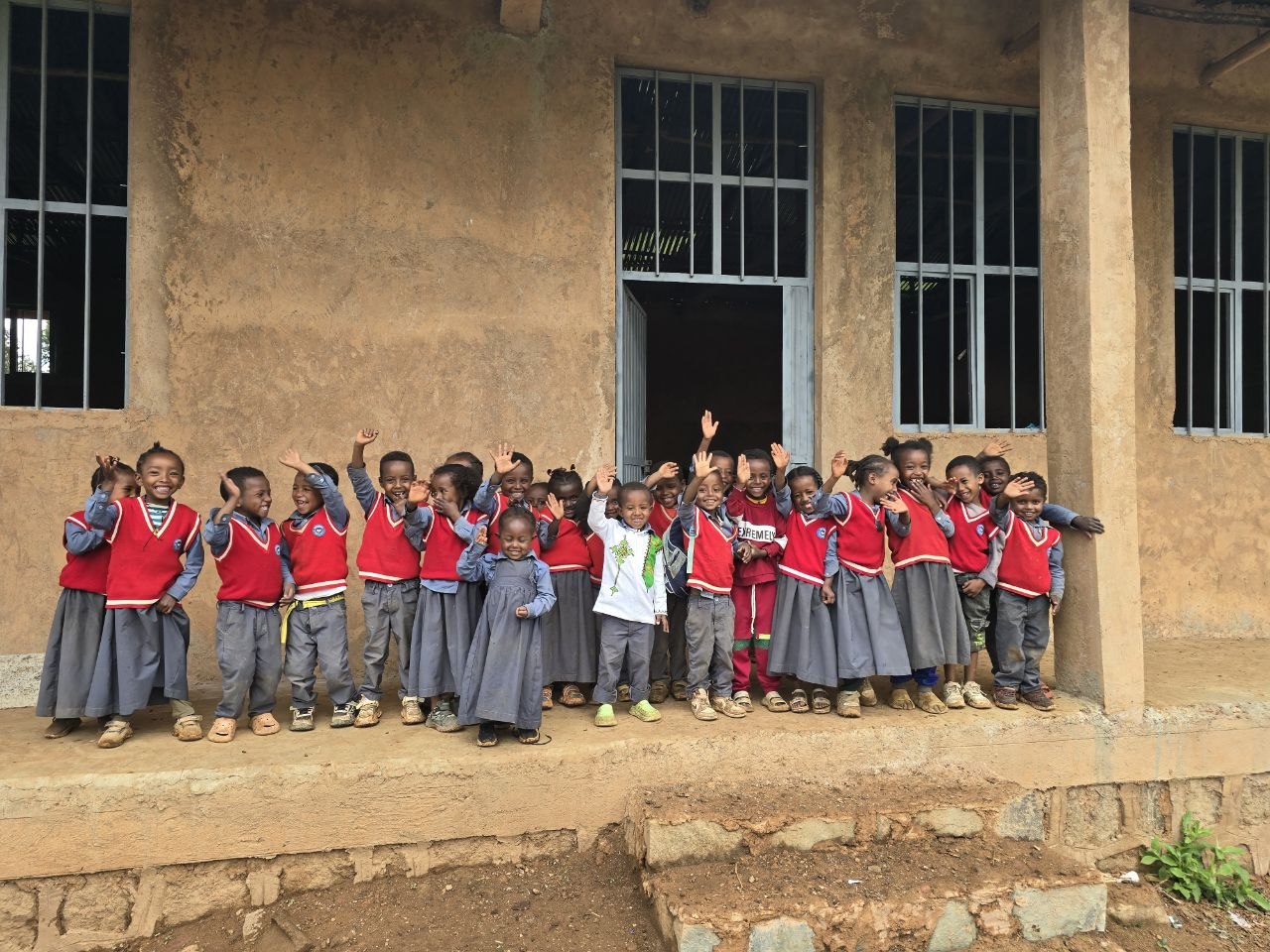 Children waving outside the kindergarten Gallica built